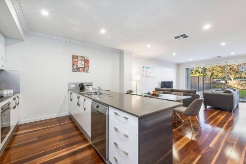 a kitchen with white cabinets and a living room at Coastal Parkside - Glenelg North - C21 SouthCoast Holidays in Glenelg