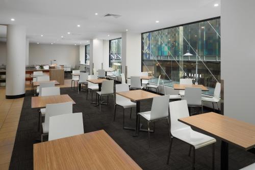 a dining room with tables and white chairs at Mercure Welcome Melbourne in Melbourne