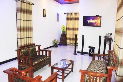 Una sala de estar con sillas, una mesa y un televisor. en Sigiri Sanu Villa, en Sigiriya