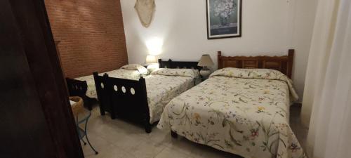 a bedroom with two beds and a brick wall at Rinconada in Taxco de Alarcón