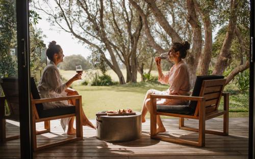 two women sitting in rocking chairs on a porch at Bangalay Luxury Villas in Shoalhaven Heads