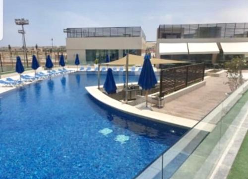 a large swimming pool with blue umbrellas and chairs at Hacienda bay in El Alamein