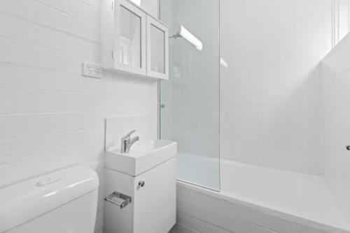 een witte badkamer met een wastafel en een toilet bij Sublime 1-Bed Apartment by Royal Park in Melbourne