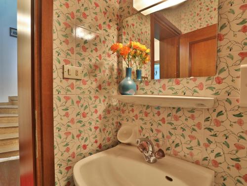 a bathroom with a sink and a mirror and flowers at Villa Atelier Baron Killi in Caldaro