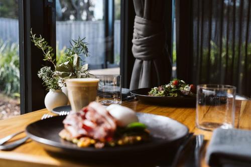 a wooden table with two plates of food on it at Bangalay Luxury Villas in Shoalhaven Heads