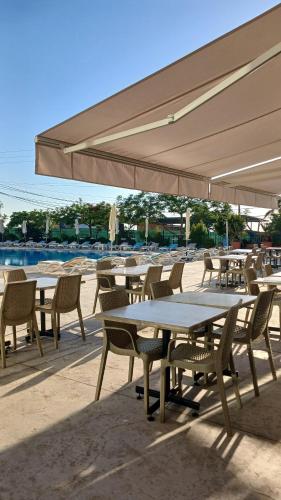 a group of tables and chairs under an umbrella at Le Six Hotel And Resort in Batro&ucirc;n