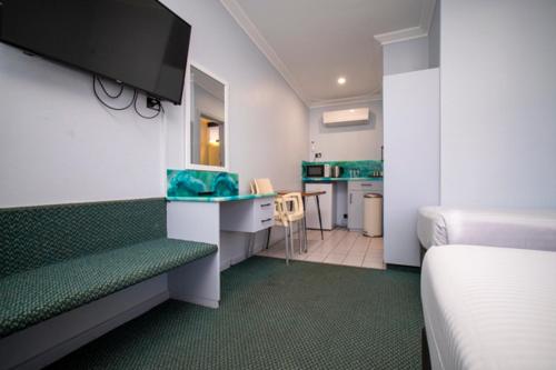 a hotel room with a bed and a desk and a kitchen at Manjimup Motor Inn in Manjimup