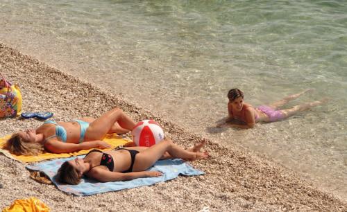 three girls laying on the beach near the water at Tourist Settlement Brzet in Omiš