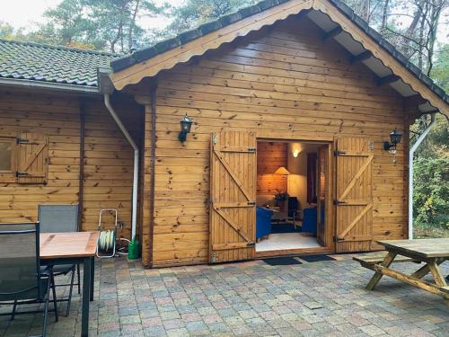 a large wooden cabin with a large door at Vakantiehuis midden in het bos vlakbij de Efteling Natuurhuisje Loonse en Drunense duinen in Helvoirt