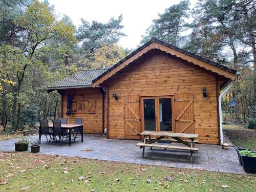 a wooden cabin with a table and a picnic table in front at Vakantiehuis midden in het bos vlakbij de Efteling Natuurhuisje Loonse en Drunense duinen in Helvoirt