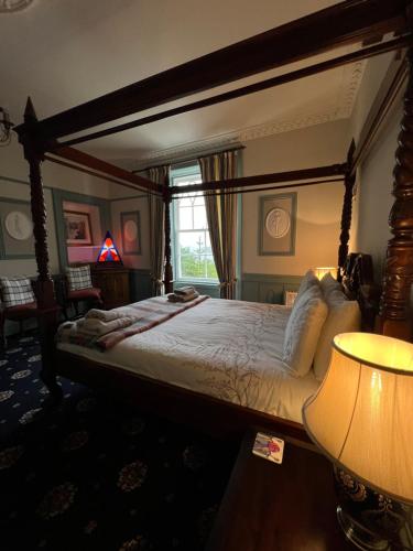 1 dormitorio con cama con dosel y ventana en Ivybank Villa, en Rothesay