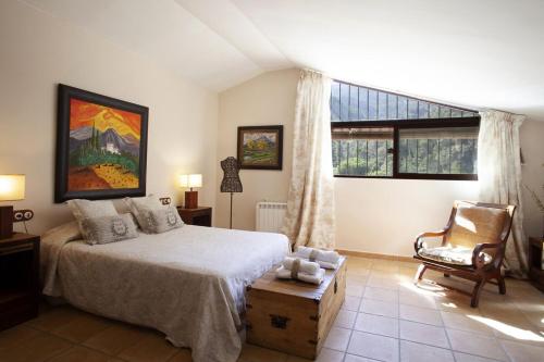 a bedroom with a bed and a chair and a window at Finca la Noguera-Sierra Cazorla in Quesada