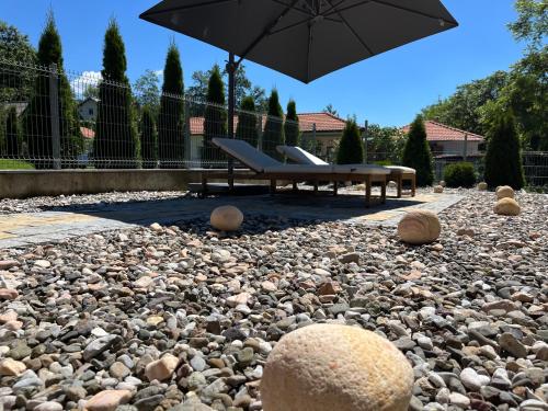 a patio with a bench and an umbrella and rocks at Vip kuca Banja Vrujci in Popadić
