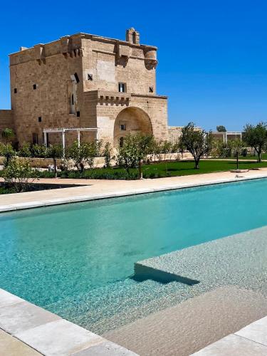 a large swimming pool in front of a castle at Masseria Donna Menga - The Leading Hotels of the World in Torre Lapillo