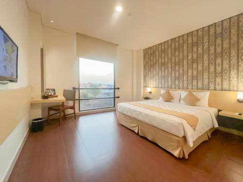 - une chambre avec un grand lit et une grande fenêtre dans l'établissement Hotel 88 Embong Malang Surabaya By WH, à Surabaya