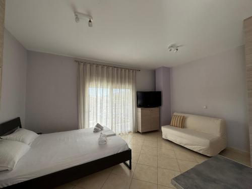 a bedroom with two beds and a flat screen tv at NikLuDin suites & studios in Laganas