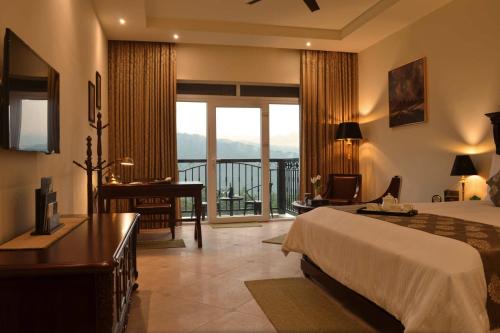 Montrose Golf Resort and Spa - Coorg في Jambur: غرفة نوم بها سرير ومكتب وشرفة