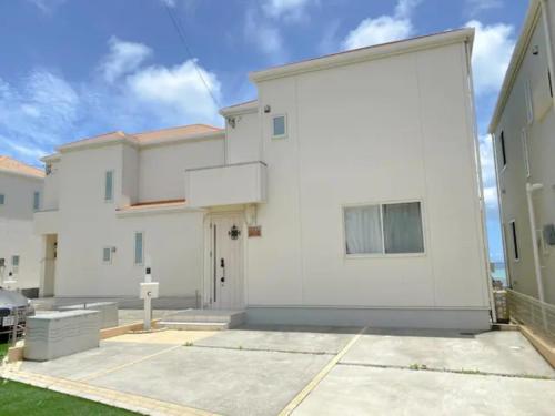 a large white building with a parking lot at グランディオーソオーシャンビューヴィラ金武1 in Okinawa City