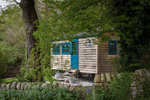 a tiny house with blue windows and a ladder at Woodlands Shepherds Hut Chatsworth Estate in Baslow