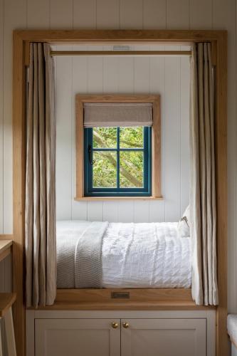 a bed in a room with a window at Woodlands Shepherds Hut Chatsworth Estate in Baslow