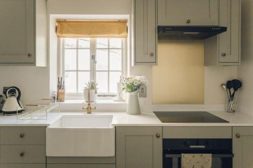 a white kitchen with a sink and a window at Keepers CottageChatsworth Estate in Baslow