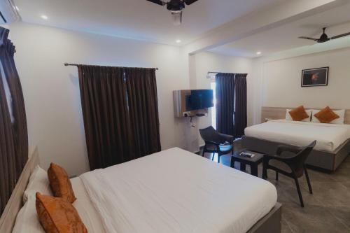 a hotel room with two beds and a tv at Amber Rooms in Porvorim