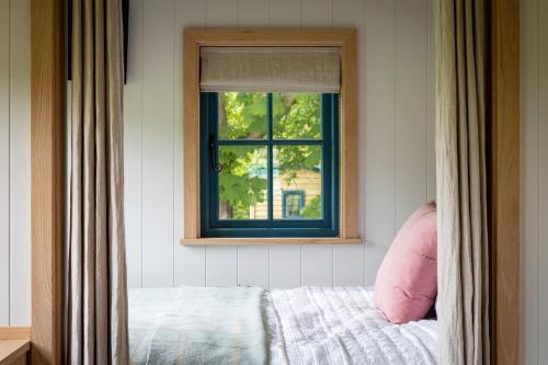 a window in a bedroom with a bed and a window at Oak Tree Shepherds Hut Chatsworth Estate in Baslow