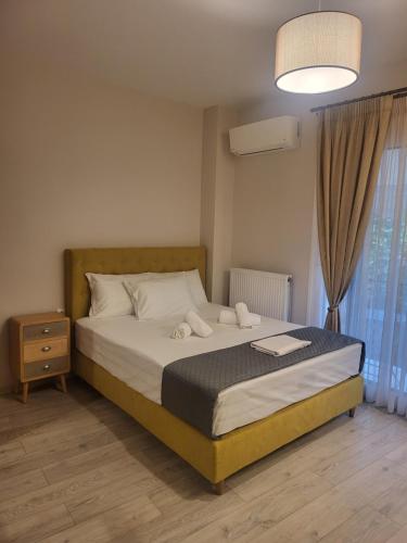 a bedroom with a large bed with a nightstand and a window at Platanakia Houses in Ioannina