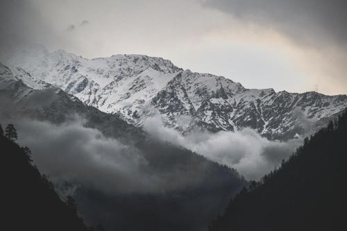 a snow covered mountain with clouds in front of it at Triumph bed and breakfast and cafe in Kasol