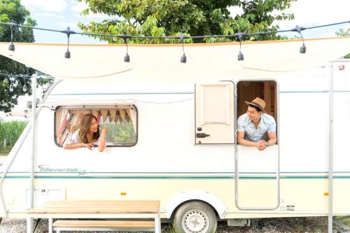 a man and a woman sitting in an rv at The Campster Kanchanaburi in Kanchanaburi City