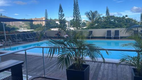 uma palmeira sentada ao lado de uma piscina em The place to be em Noumea