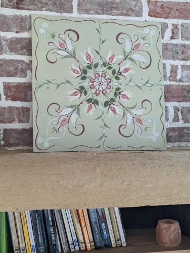 a painting of a flower on a shelf with books at Vivez dans un magnifique village Normand in La Carneille