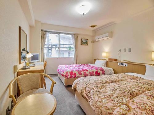 a hotel room with two beds and a table and a window at Kumagaya Royal Hotel Suzuki in Kumagaya