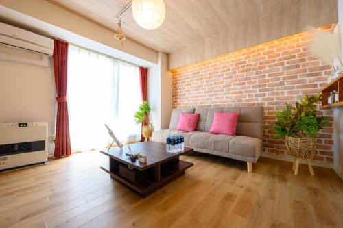 a living room with a couch and a brick wall at Nakajima Park Hotel AMS tower Nakajima 20F 2001 in Sapporo
