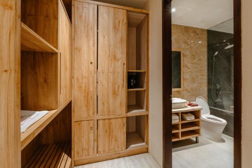 a bathroom with wooden cabinets and a toilet and a shower at Bali Sunshine Nusa Dua in Nusa Dua