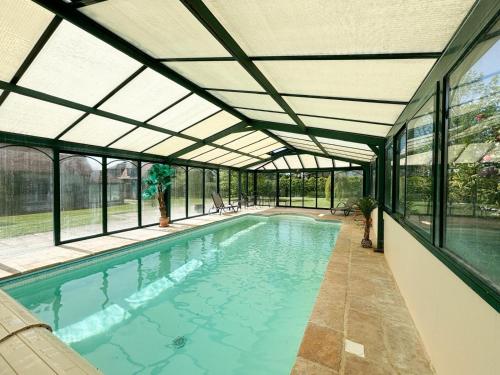 une piscine intérieure avec un plafond en verre dans l'établissement La Maison du Tilleul avec Piscine couverte chauffée, à Saint-Sulpice-sur-Risle