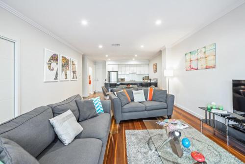 a living room with two couches and a television at Coastal Parkside - Glenelg North - C21 SouthCoast Holidays in Glenelg