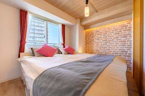 a bedroom with a bed with a brick wall at Nakajima Park Hotel AMS tower Nakajima 20F 2001 in Sapporo