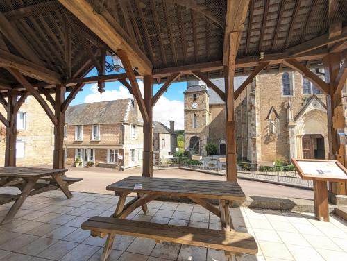 two picnic tables in a pavilion with a church at Vivez dans un magnifique village Normand in La Carneille