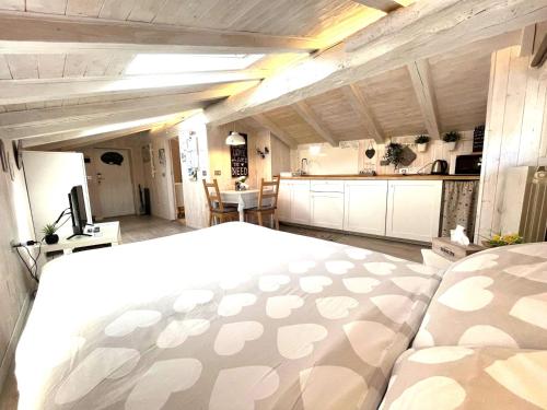 una camera con un grande letto bianco e una cucina di Il piccolo Loft nel cuore antico di Aosta - You & Me case vacanza ad Aosta