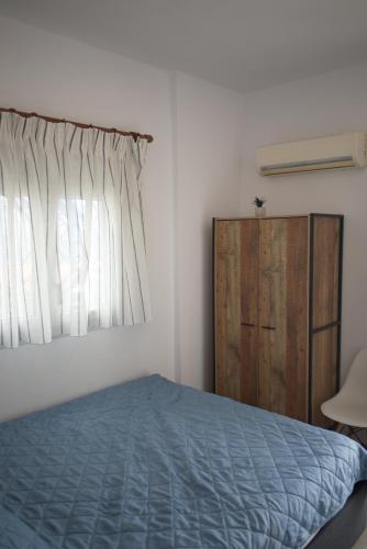 a bedroom with a blue bed and a window at Sufiko Studios - Thea in Armenistis