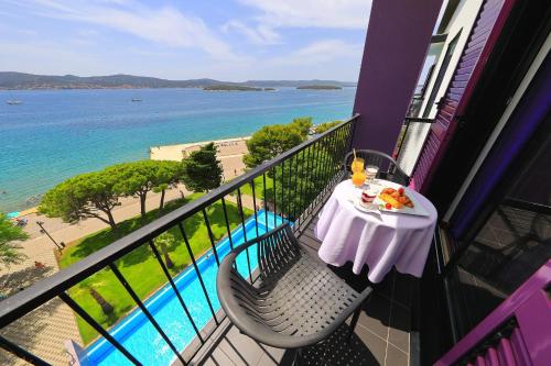a table and chairs on a balcony with a view of the ocean at Ilirija Resort Hotel Adriatic in Biograd na Moru
