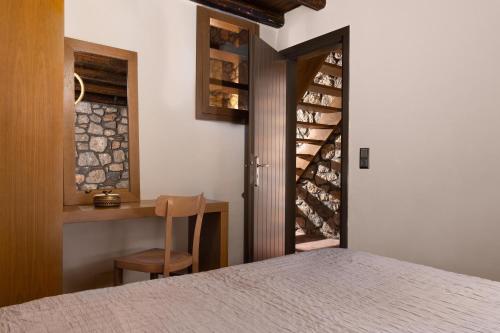 a bedroom with a bed and a table with a chair at Stone Luxury Suites - Adults Only in Archangelos