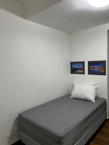 a bed in a room with two pictures on the wall at Hostal CASA FRANCISCANA in Quito