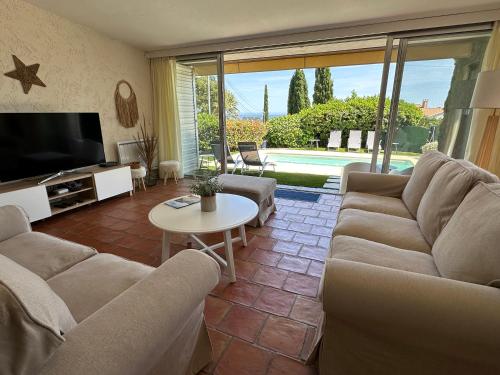 a living room with a couch and a tv and a table at Villa MahJong Piscine Vue Mer Clim 6 adultes et 2 enfants in Cavalaire-sur-Mer