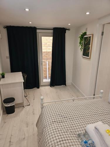 a bedroom with a bed and a desk and a window at Modern Double Room in Dartford- Private Entrance in Kent