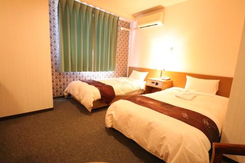 a hotel room with two beds and a window at ホテル東伯イン in Kotoura