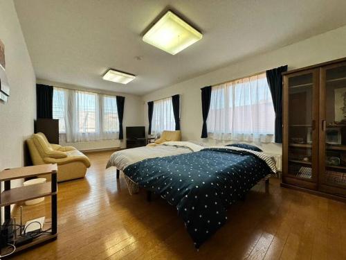 a bedroom with a bed and a couch and windows at Shakotan Detached House Stay in Shakotan