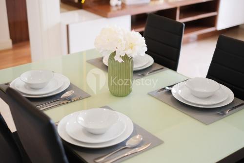 a table with white plates and a vase of flowers at Bhumi by Kozystay - Paskal in Bandung
