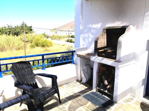 un patio con camino e una sedia sul balcone. di Angelina Greek House a Paroikia